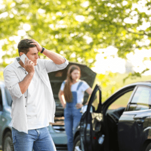 a man calling someone on the phone with hands on his head worrying over a car accident
